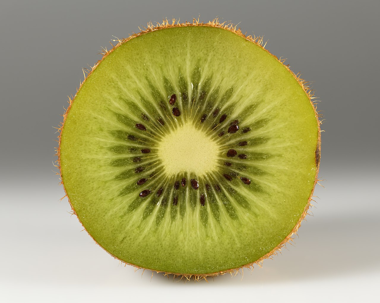 Centro verde di un kiwi tagliato, con semi scuri e fibre radiali